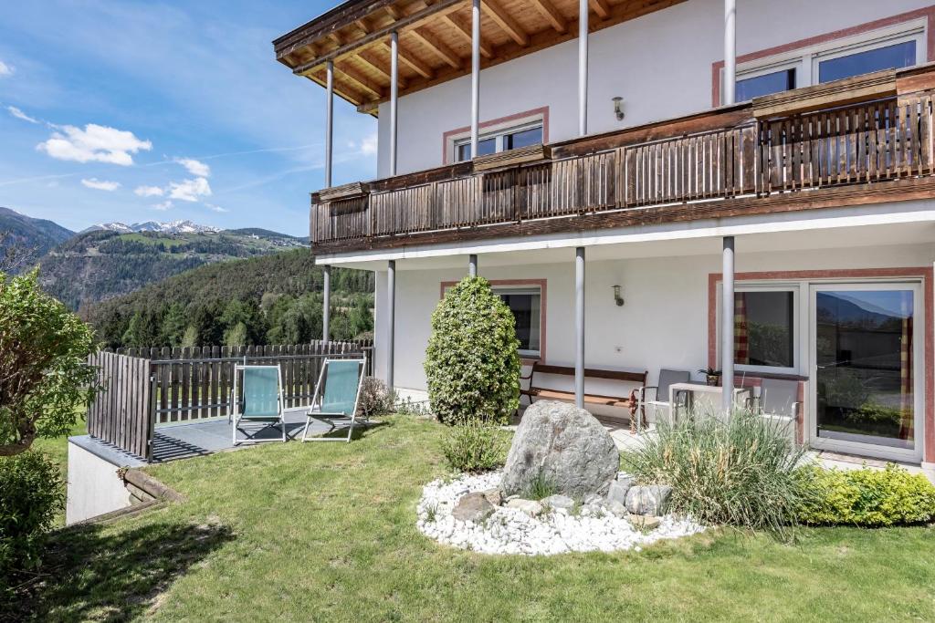 dom z balkonem i dwoma krzesłami na dziedzińcu w obiekcie Panorama Residence Schlossblick w mieście Rodeneck