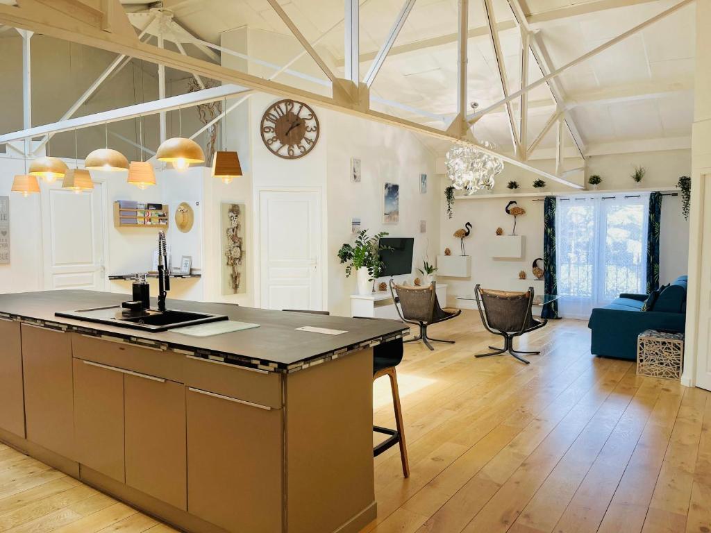 a kitchen and living room with a clock on the wall at Loft Évasion - Loft lumineux et climatisé entre Montpellier et les plages - 2 chambres - Parking - Tram in Lattes