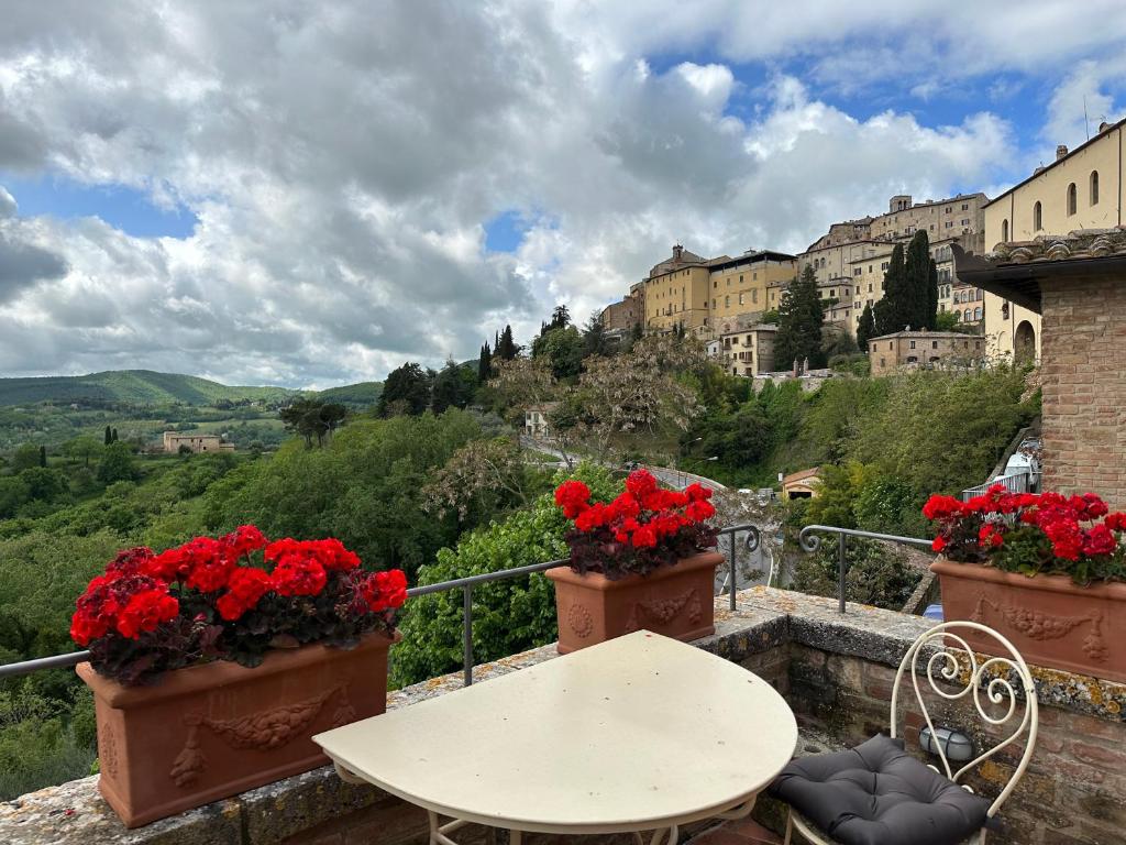 uma mesa e cadeiras numa varanda com flores vermelhas em Tuscan Palace - Buratti em Montepulciano