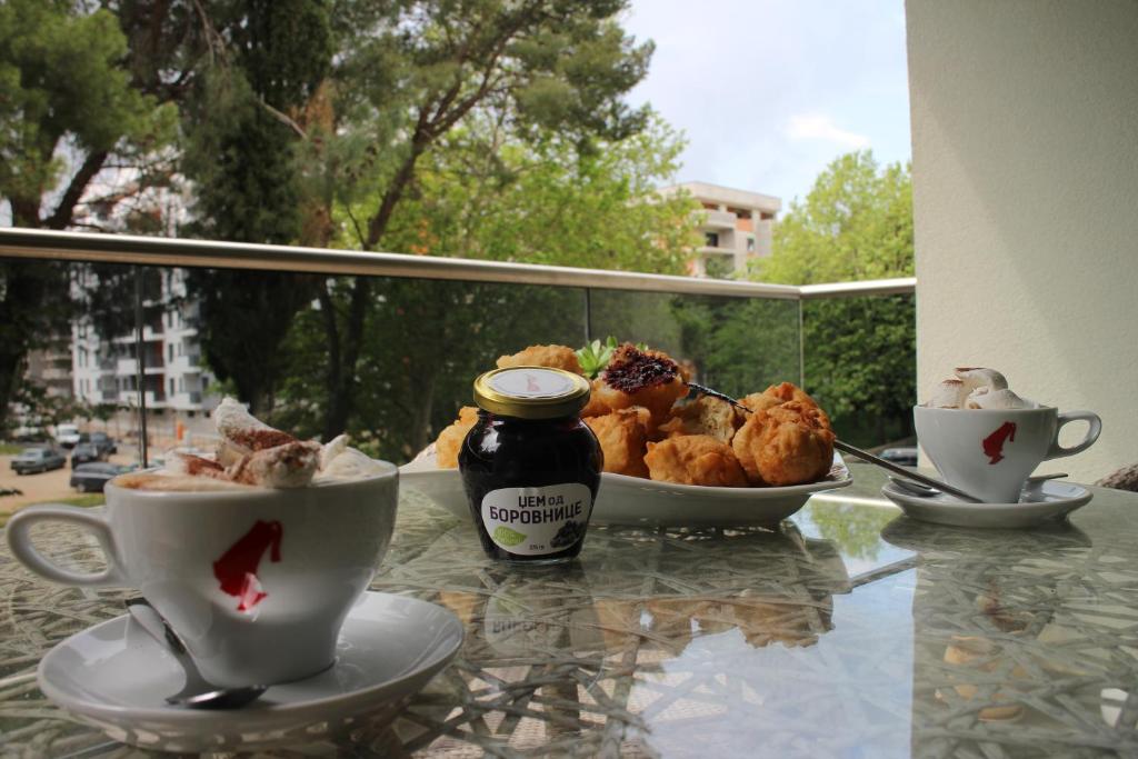 een tafel met kopjes thee en gebak op een balkon bij Apartman Mama in Trebinje