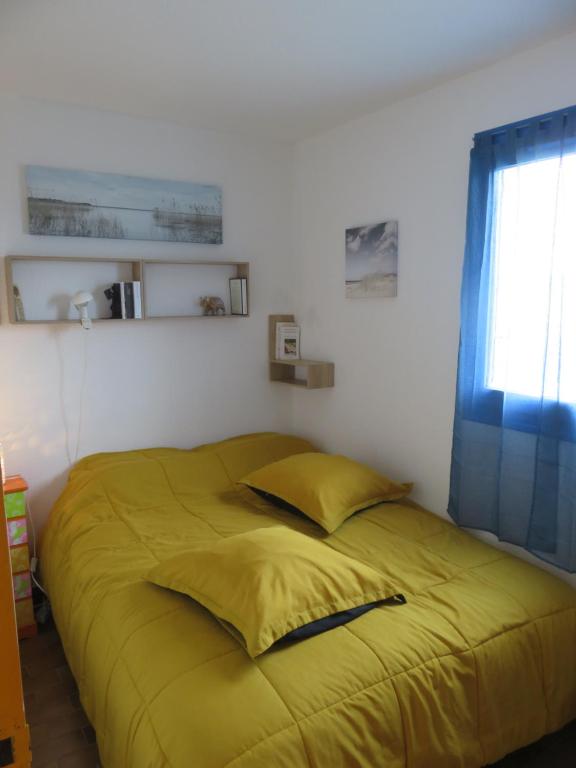 - un lit jaune dans une chambre avec fenêtre dans l'établissement Les Sables d'Or, à Le Castellas