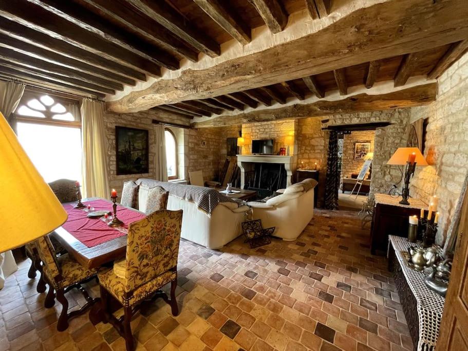Maison des gardiens du château في Béru: غرفة معيشة مع طاولة وأريكة ومدفأة