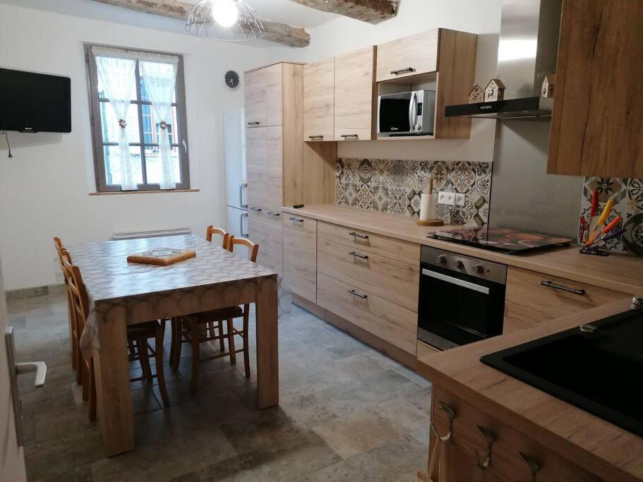 a kitchen with a wooden table and a dining room at Agréable maison de village. in Castellane