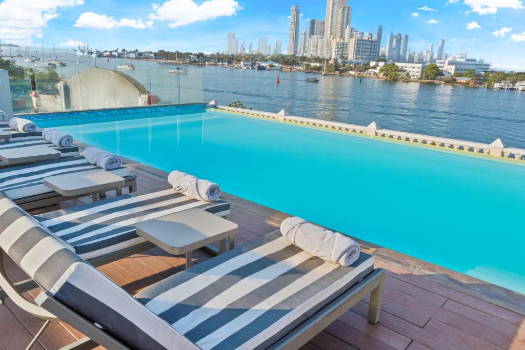 een zwembad met ligstoelen en uitzicht op het water bij GHL Arsenal Hotel in Cartagena