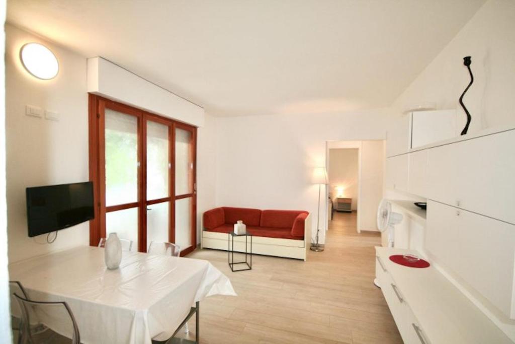 sala de estar con mesa blanca y sofá rojo en DUNA FIORITA PREMIUM en Lignano Sabbiadoro