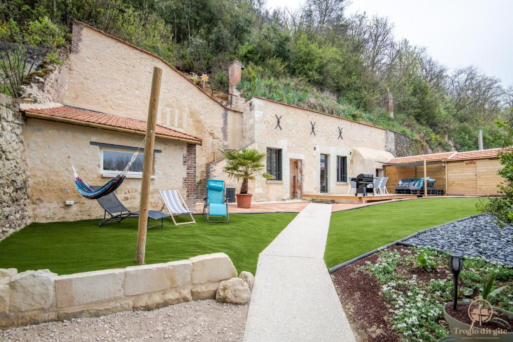 una casa con un patio con césped sidx sidx sidx sidx en Troglo Dit Gîte 4* proche d'Amboise, en Nazelles