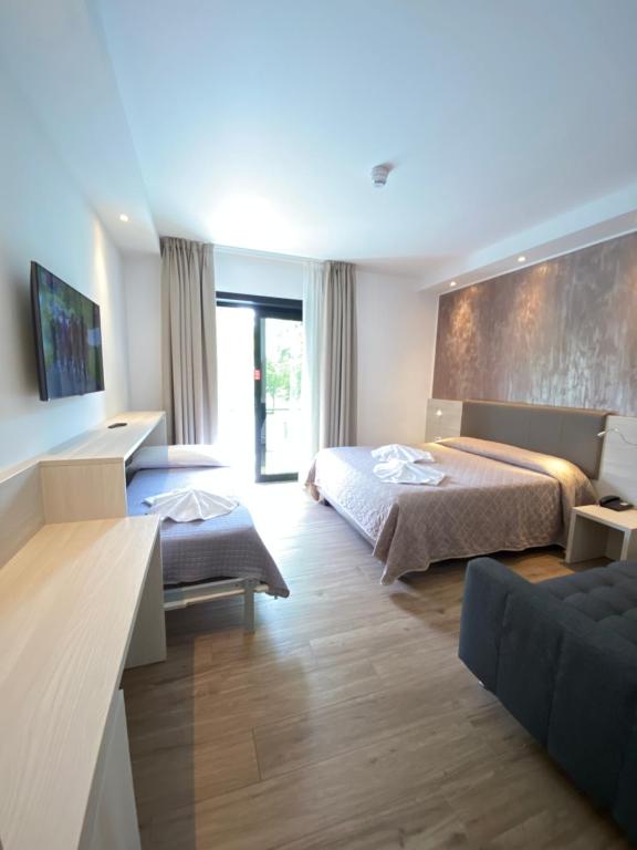 Habitación de hotel con 2 camas y sofá en Hotel Aldebaran, en Lido di Jesolo