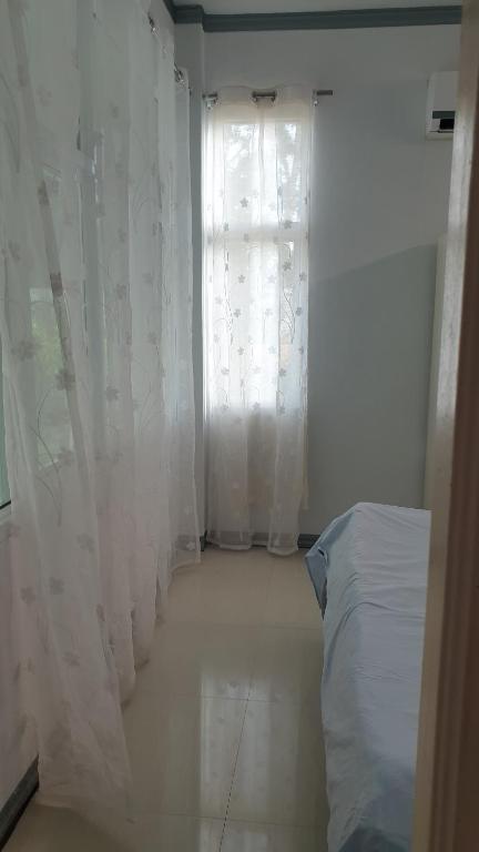a bedroom with a bed and a window with curtains at บ้านOrman in Chumphon