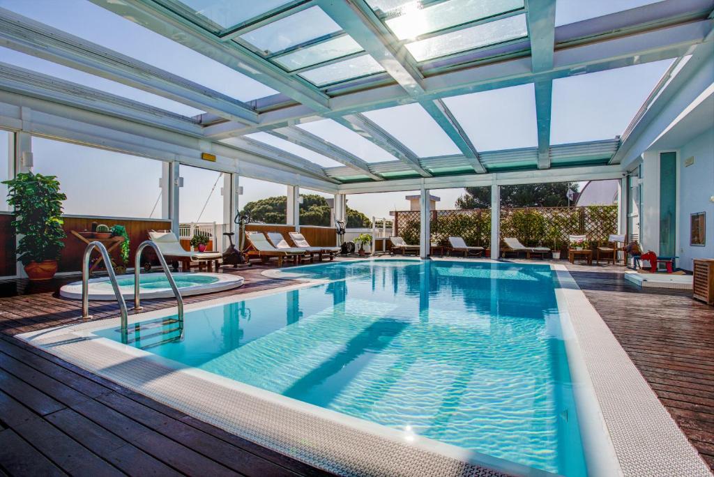 una piscina coperta con tetto in vetro e un piscina con idromassaggio di Aparthotel England a Riccione