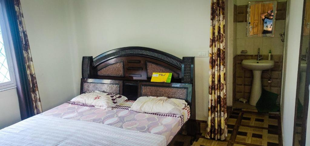 a bedroom with a bed with a wooden headboard and a sink at Gaharwar Home Stay in Dehradun