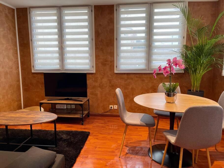 a living room with two tables and chairs and two windows at Appartement cosy terrasse parking 20 mn Paris in Savigny-sur-Orge