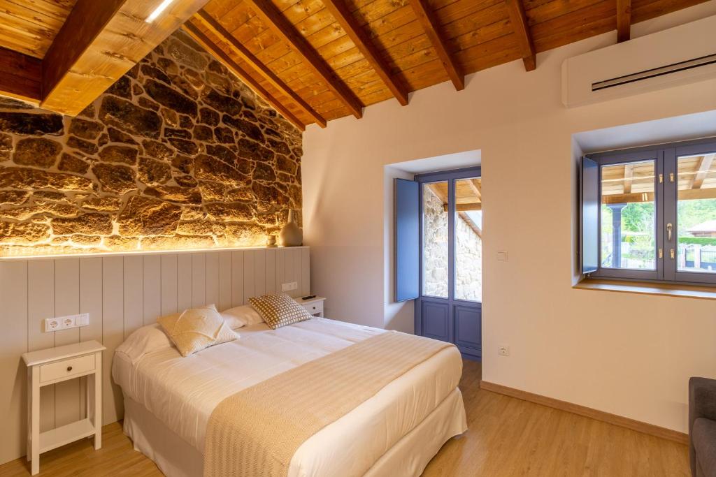 1 dormitorio con cama y pared de piedra en Alojamiento Turístico Caxide Parada de Sil Ribeira Sacra, en Parada del Sil