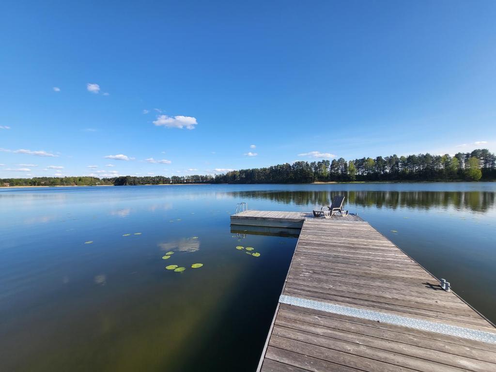 a dock with a chair sitting on top of a lake at Orli Zakątek in Gorczyca