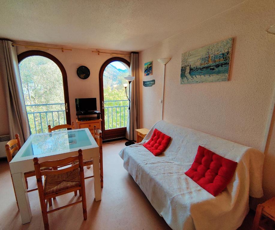 a living room with a bed with red pillows on it at Appartement T2 CABINE Résidence Eugénie in Luz-Saint-Sauveur