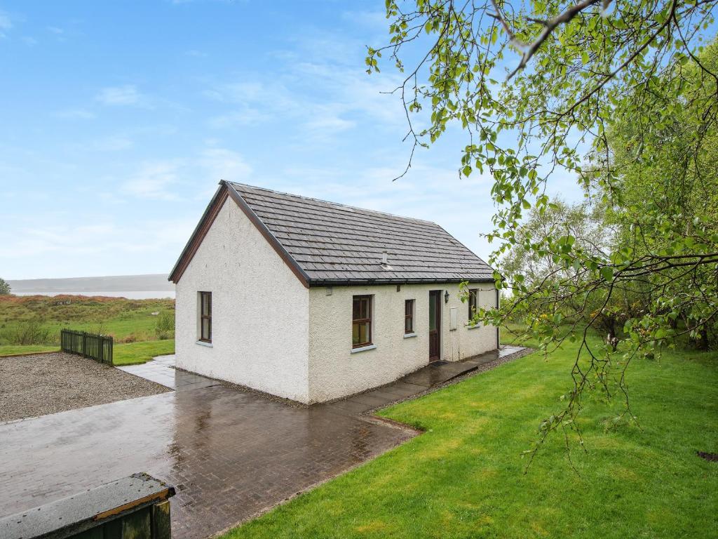 a small white house with a grass yard at Cruinn in Taynish