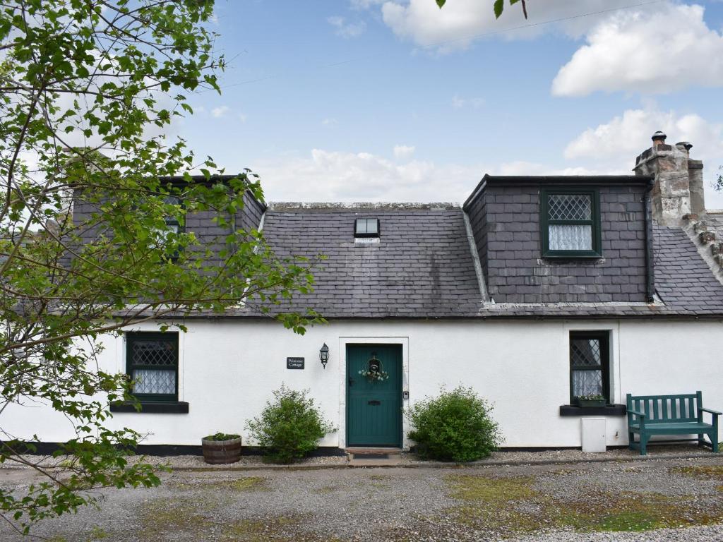 a white house with a green door and a bench at Primrose Cottage in Elgin