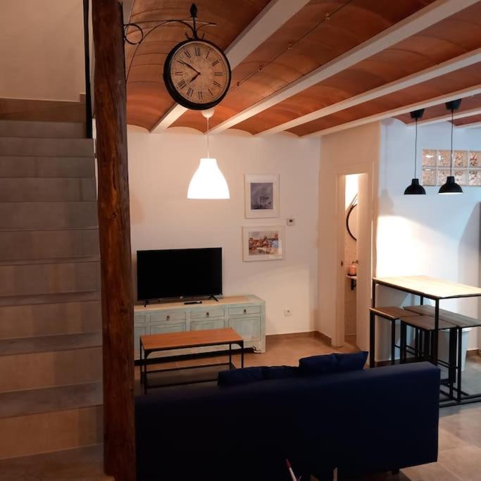 a living room with a tv and a clock on the wall at Casa rural La Azuleja de Alatoz in Alatoz