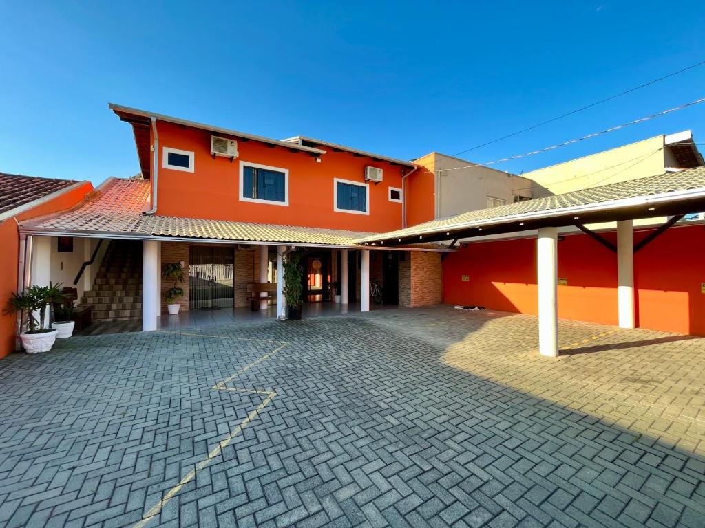 a red building with a cobblestone parking lot at Parada do Parque Hotel in Penha