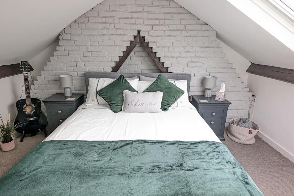 um quarto com uma cama grande e almofadas verdes e brancas em Stunning Victorian Terrace in the Golden Triangle em Norwich