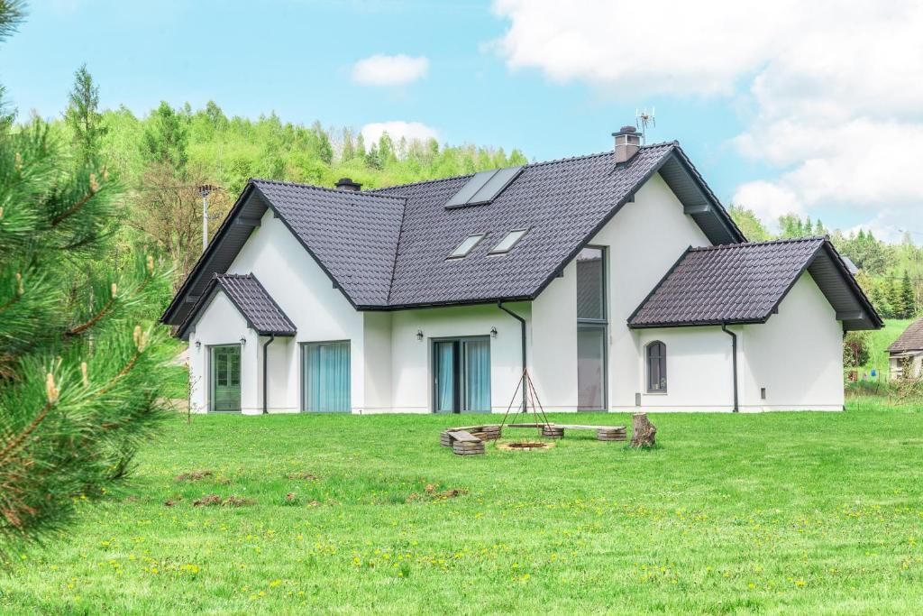 ein weißes Haus mit schwarzem Dach auf einem Hof in der Unterkunft The Modern House in Raciechowice