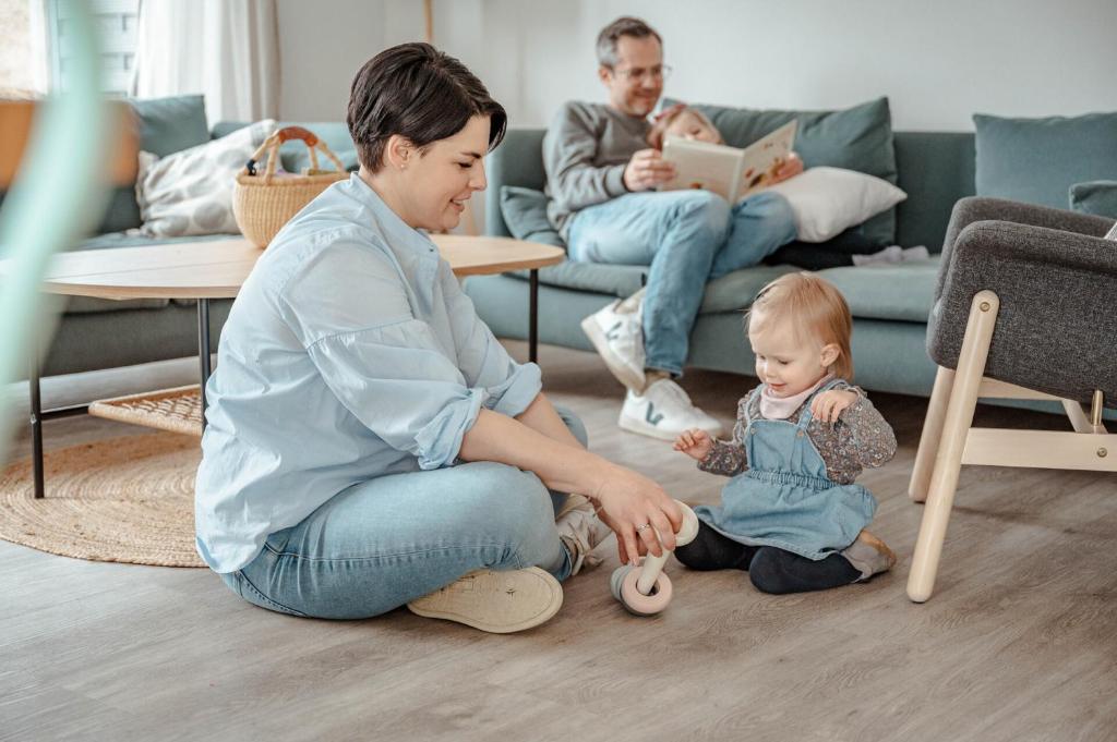 una mujer sentada en el suelo con un bebé en una sala de estar en Ferienhaus am Mühlenweiher 2 en Leutkirch im Allgäu