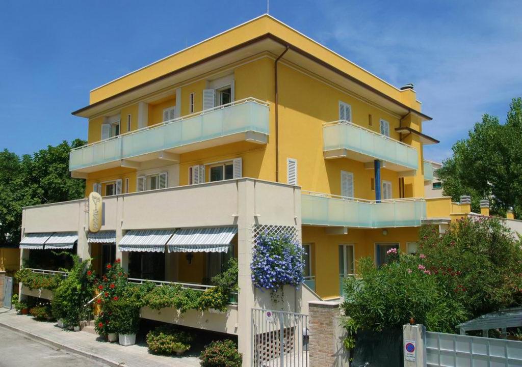 un edificio amarillo con balcón en una calle en Hotel Vienna, en Senigallia