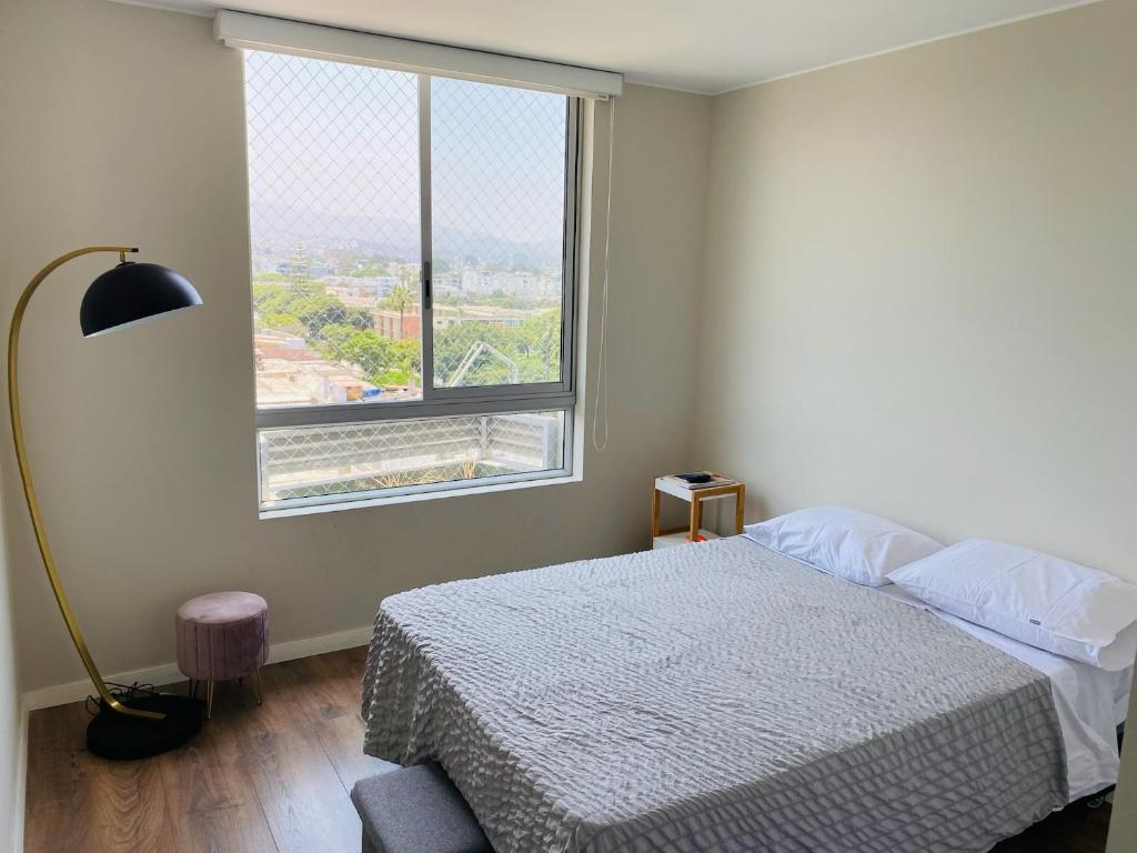 a bedroom with a bed and a large window at Habitación en miraflores in Lima