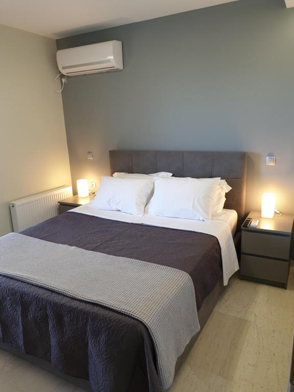 ein Schlafzimmer mit einem großen Bett mit zwei Nachttischen in der Unterkunft Stergiou Luxury Apartments with shared pool in Anavyssos