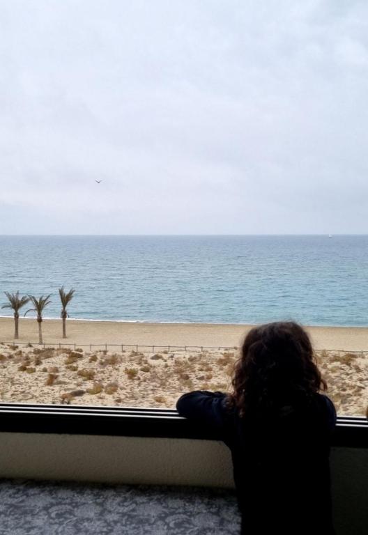 une personne donnant sur la plage par une fenêtre dans l'établissement Duplex 2 chambres vue panoramique Mer, au Barcarès