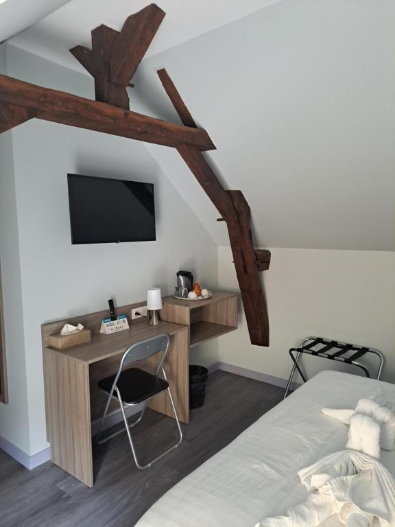 a bedroom with a bed and a desk and a tv at Le petit Védaquais in Vaas