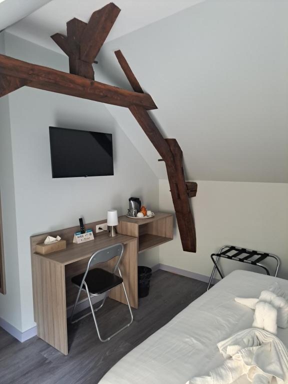 una camera da letto con un letto, una scrivania e una TV di Le petit Védaquais a Vaas