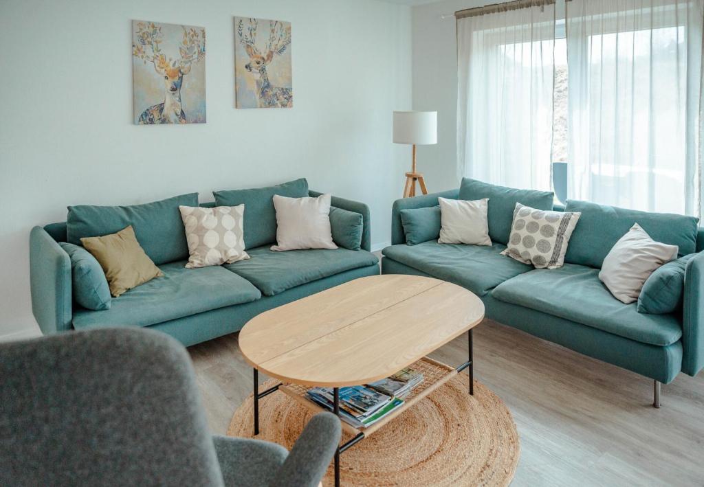 ein Wohnzimmer mit einem blauen Sofa und einem Tisch in der Unterkunft Ferienhaus am Mühlenweiher 3 in Leutkirch im Allgäu