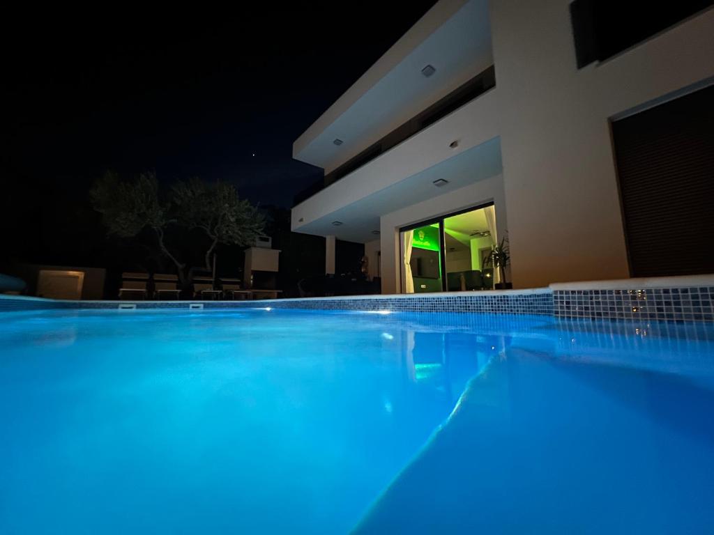 a swimming pool at night with blue lights at Sunluxvilla ,Heated Pool, IR Sauna in Kaštela