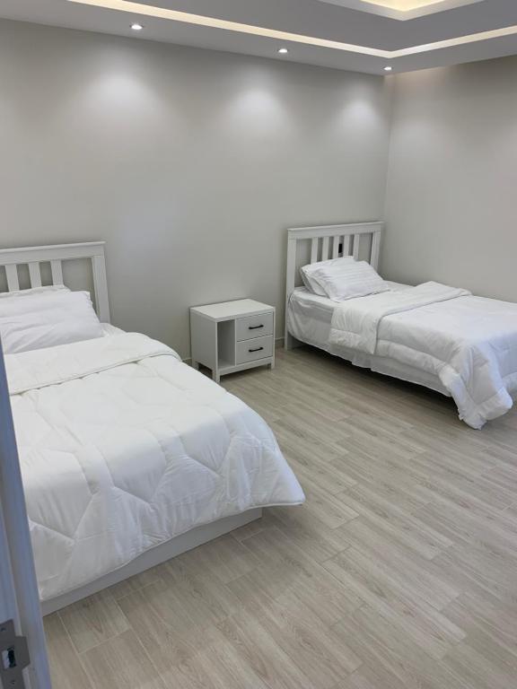 two beds in a bedroom with white walls at شاليه اوبل قاردن - OPAL GARDENS in Al Baha