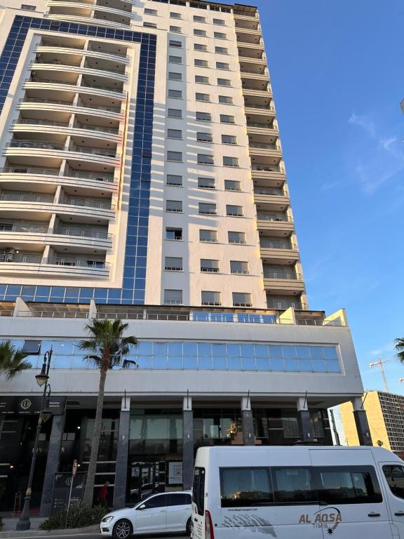 a white van parked in front of a tall building at Moroccan Floors - Suites Appart-Hôtel in Tangier