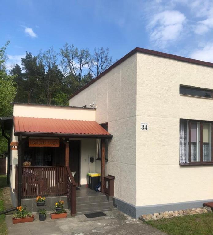 a white building with a porch and a balcony at Dom pod lasem in Ruciane-Nida