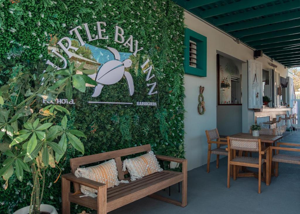 a green wall with a bench and a sign on it at Turtle Bay Inn in Lajas