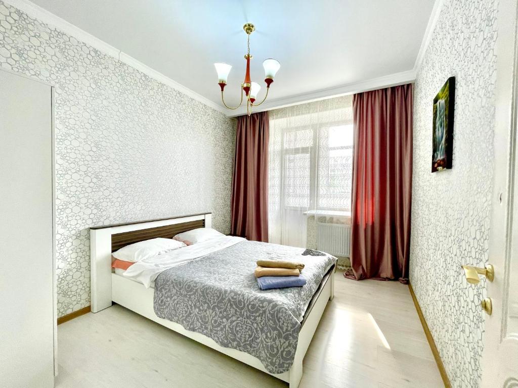 a bedroom with a bed and a red curtain at апартаменты с видом на город in Pavlodar