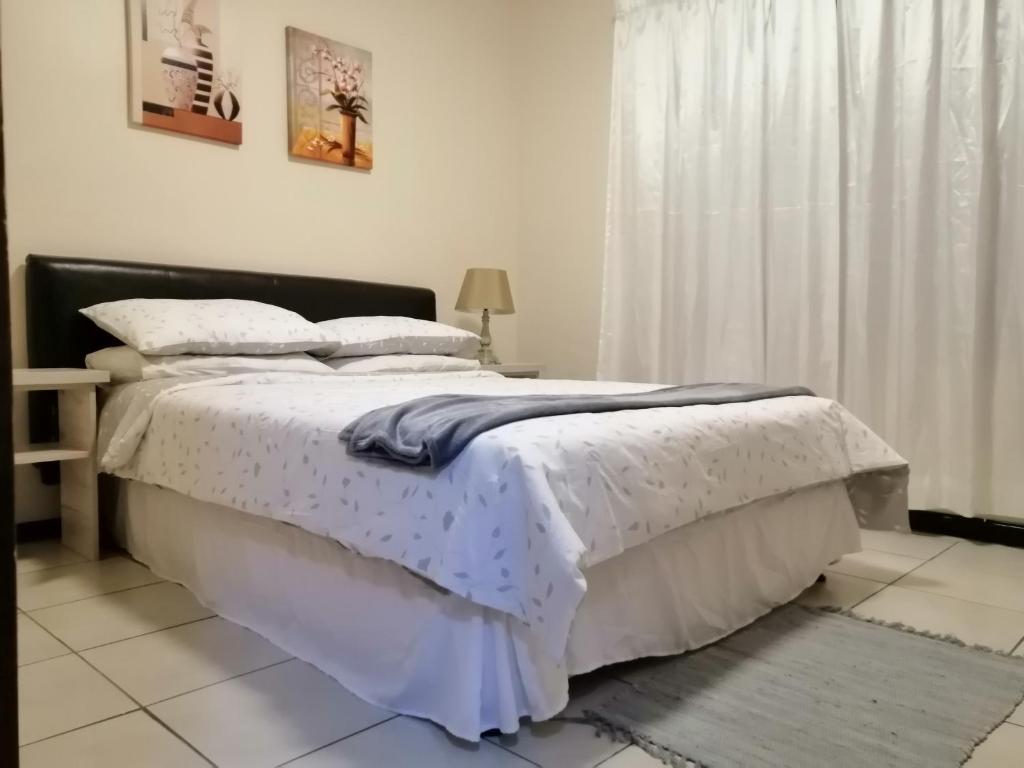 a bedroom with a large bed with white sheets at Villa Pretoria in Pretoria
