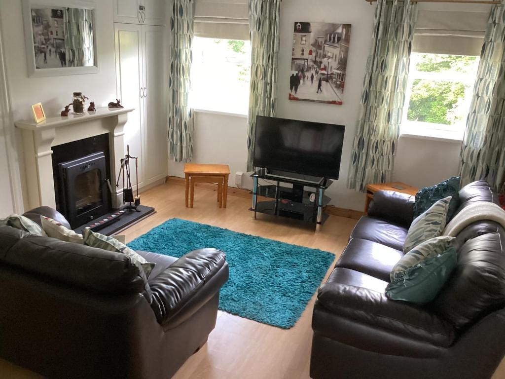 a living room with two leather couches and a fireplace at Riverview Apartment in Buncrana