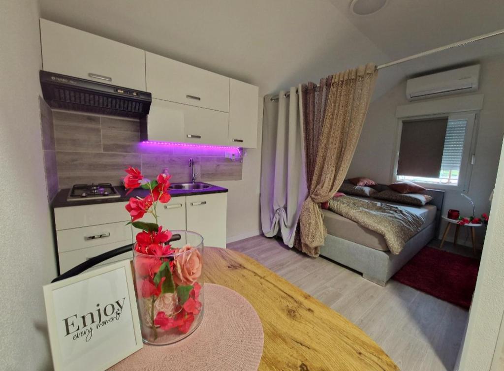 a kitchen and living room with a table with flowers on it at STUDIO APP & Beauty Loza in Zambratija