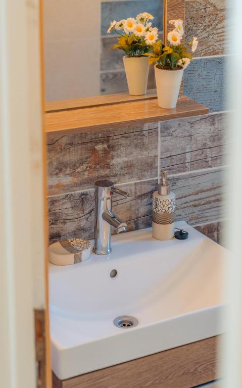 a bathroom sink with two flowers on a shelf at Houses at Chrisopigi Sifnos in Chrisopigi