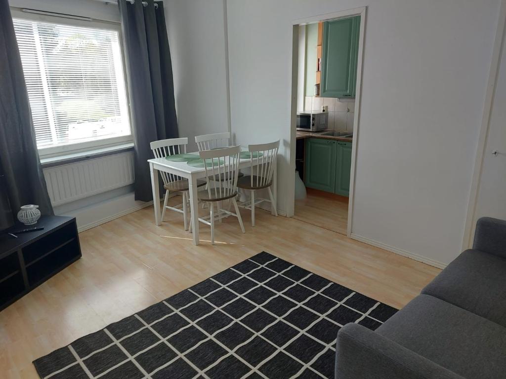 a living room with a table and chairs and a kitchen at Kiertokatu apartment in Pori