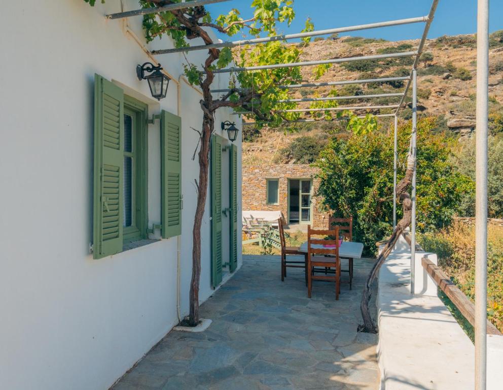 a patio with green shutters and a table and chairs at Houses at Chrisopigi Sifnos in Chrisopigi