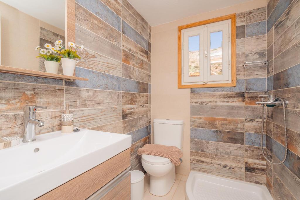 a bathroom with a toilet and a sink and a window at Houses at Chrisopigi Sifnos in Chrisopigi