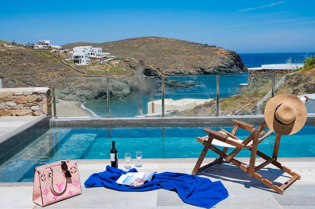 Merchia Beach的住宿－Miramare Suites Mykonos，游泳池畔的椅子和一瓶葡萄酒