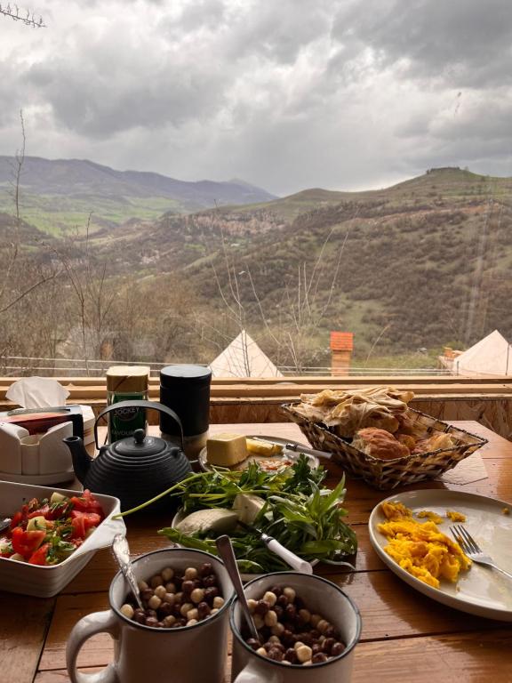 a table with plates of food on a table with a view at Alereks Mountain Camping in Dsegh