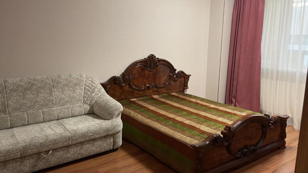 a bed and a couch in a living room at Уютная квартира на левом берегу Астаны in Taldykolʼ