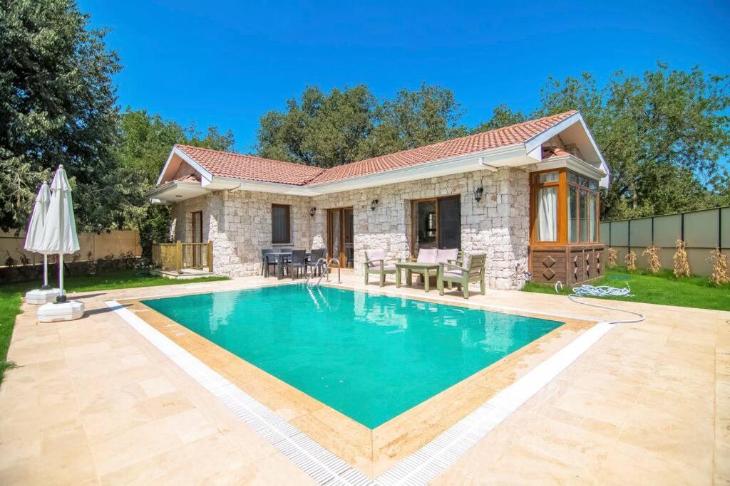 a villa with a swimming pool in front of a house at Kayaköyde Havuzlu Bahçeli Villa in Fethiye