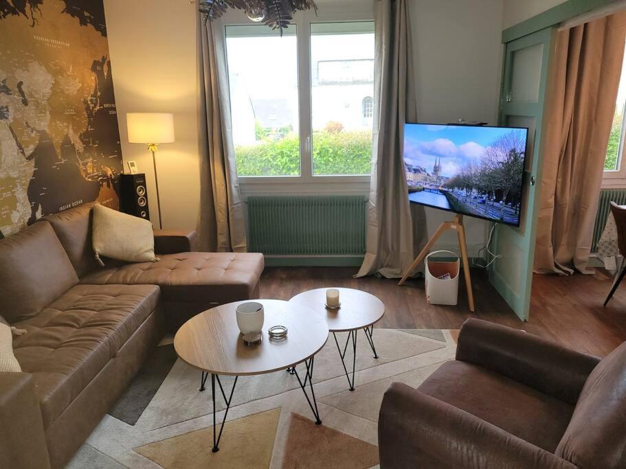 un salon avec un canapé, une table et une télévision dans l'établissement maison 2 chambres spa centre ville spa, à Quimper